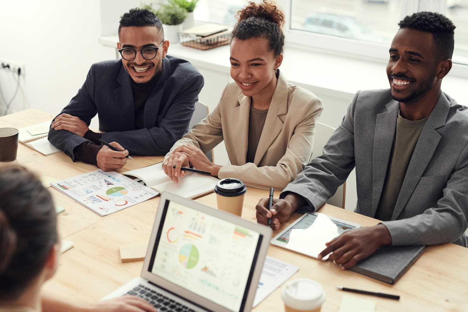 A diverse team smiling in a meeting room, reviewing charts